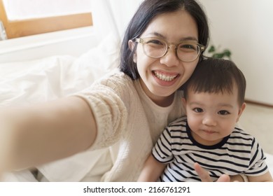 Chinese Young Mother And Her Little Cute Son Using Smartphone Taking Selfie Photos, Single Mom, Happy Asian Family, Smiling Faces.