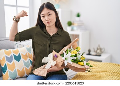 Chinese Young Woman Holding Bouquet Of White Flowers Strong Person Showing Arm Muscle, Confident And Proud Of Power 