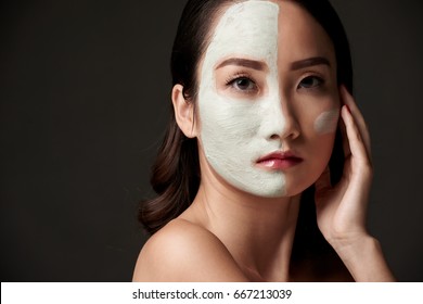 Chinese young woman with white clay mask on her face looking at camera