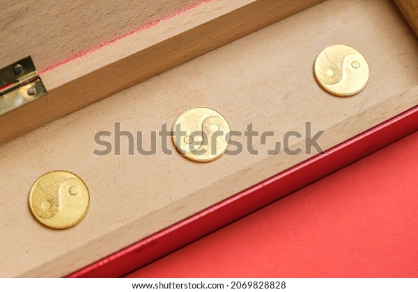 I ching ancient Chinese oracle, Book of\
Changes or Classic of Changes. Old coins on a vintage wooden box\
with red background