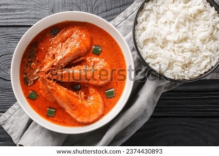 Chingri malai curry also known as prawn malai curry made from tiger and king prawns and coconut milk and flavoured with spices closeup on the wooden table. Horizontal top view from above
