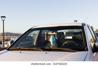 Chinstraps, Disposable Masks Hanging From A Rearview Mirror Of A Parked Car.