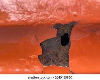 Chipped Paint And Rusted Out Hole On Orange Vintage Truck Detail