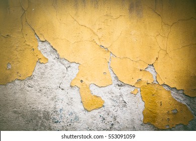 Chipping yellow plaster paint on white stone wall 