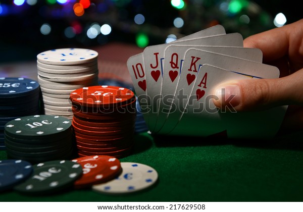 Chips and\
cards for poker in hand on green\
table
