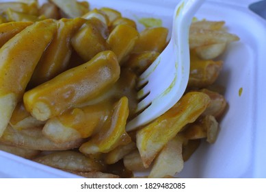 Chips And Curry Sauce In A Polystyrene Container With Plastic Fork