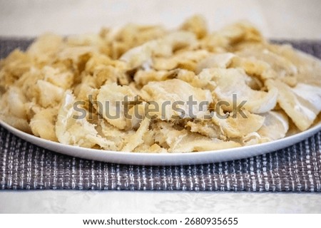 chips of gadus macrocephalus cod fillet, salted and dried, on a round white plate