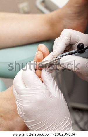 A chiropodist taking care of woman's foot - remove dry skin with a Grinder