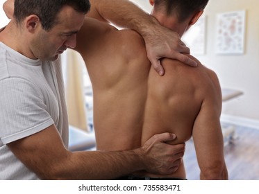 Chiropractic Back Adjustment. Muscular Man Suffering From Back And Neck Pain.