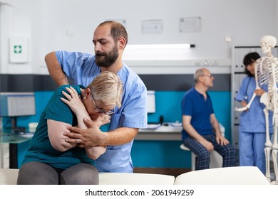 Chiropractic Specialist Cracking Back And Shoulder Bones For Retired Woman At Orthopedic Consultation. Chiropractor Giving Assistance To Elder Patient For Recovery And Rehabilitation