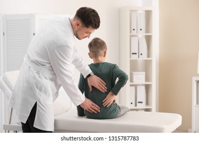 Chiropractor Examining Child With Back Pain In Clinic