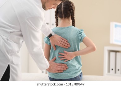 Chiropractor Examining Child With Back Pain In Clinic