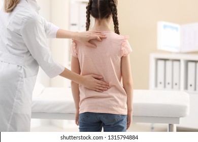 Chiropractor Examining Child With Back Pain In Clinic