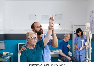 Chiropractor holding arm of old woman to relieve pressure for recovery in osteopathy office. Orthopedic assistant helping senior patient with shoulder muscle pain for healthcare. - Powered by Shutterstock