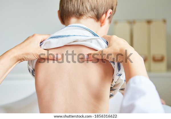 Chiropractor or osteopath does acupressure on back\
of child with back\
pain