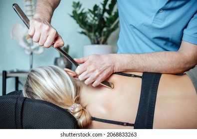 Chiropractor performing myofascial release techniques with IASTM tool for the Rhomboids - Shutterstock ID 2068833263