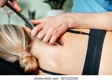 Chiropractor performing myofascial release techniques with IASTM tool for the Rhomboid muscle to relieve scapular pain - Shutterstock ID 2071232330