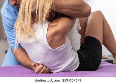 Chiropractor performing a spinal adjustment on a patient lying on a therapy table, focusing on spinal alignment, pain relief, and improving mobility and overall wellness - Powered by Shutterstock