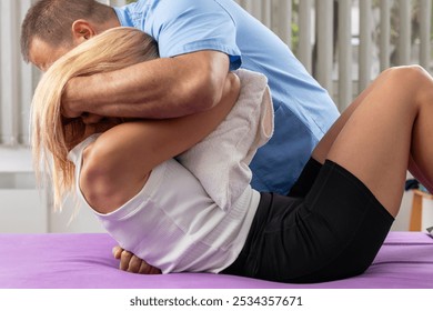 Chiropractor performing an upper back adjustment on a patient lying on a therapy table, focusing on spinal alignment, pain relief, and improving mobility and overall wellness - Powered by Shutterstock