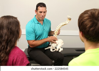 A Chiropractor showing a model of the human spine to two children - Powered by Shutterstock