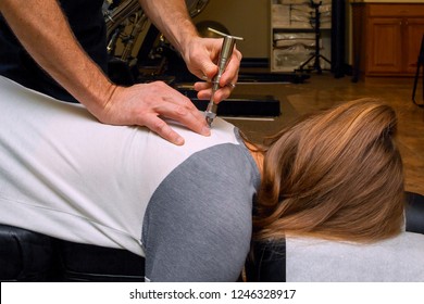 Chiropractor Uses An Integrator On The Back Of A Young Girl To Align Her Spine And Reduce Subluxation.  She Is Laying Face Down On A Chiropractic Table.