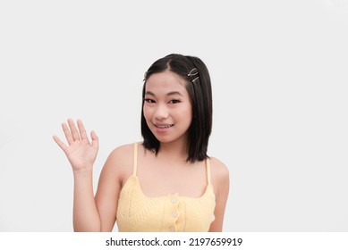 A chirpy and zestful woman says hi to the camera. A young lady posing in front of a white background. - Shutterstock ID 2197659919