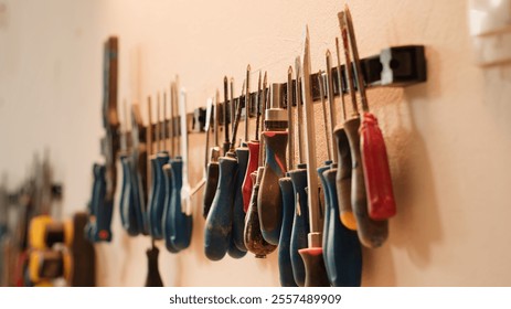 Chisels, screwdrivers, wrench and pliers on wall in carpentry studio, panning shot. Close up of various woodworking tools on rack in workshop used for repairing or creating wooden objects - Powered by Shutterstock