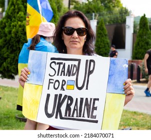 CHISINAU, MOLDOVA - CIRCA JUL 2022: Anti-war protest outside Russian embassy in Chisinau. Woman with poster "Stand up for Ukraine", Ukraine flag.