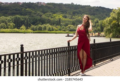 Chisinau, Moldova - June 05, 2020. Portrait of a woman in a red dress near a lake.
