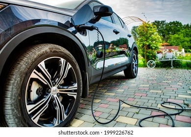 CHISINAU, MOLDOVA - JUNE 26, 2021: Electric Vehicle Charging Station For Home. Plugging In Electric Car In Front Of A Rural House.