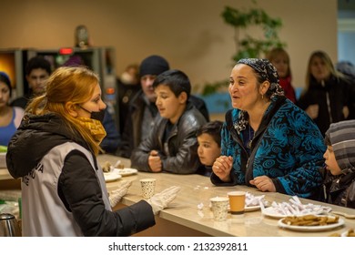 chisinau, moldova - march 4 2022: ukrainian refugee roma woman talking with a volunteer at hisinau arena refugee center