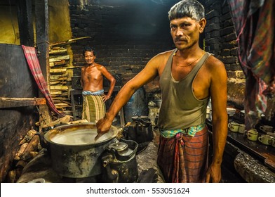 Chittagong, Bangladesh - circa July 2012: Native man stirs food in pot in kitchen in rural village near Chittagong, Bangladesh. In background with halfnaked man. Documentary editorial.