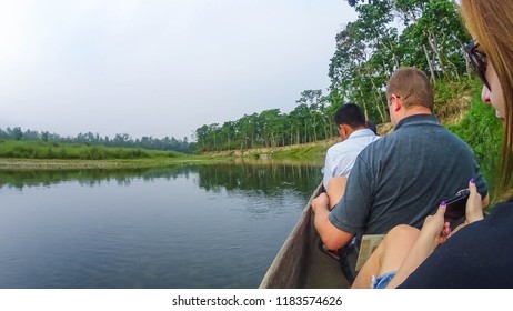 CHITWAN, Nepal - April 09, 2018: Unidentified people canoeing safari on wooden boats Pirogues on the Rapti river, in Chitwan National Park, Nepal