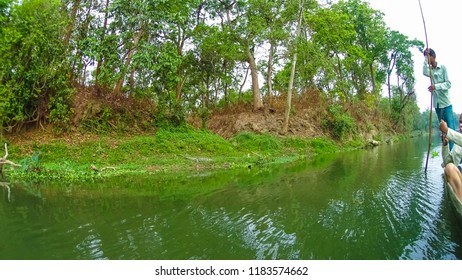 CHITWAN, Nepal - April 09, 2018: Unidentified people canoeing safari on wooden boats Pirogues on the Rapti river, in Chitwan National Park, Nepal