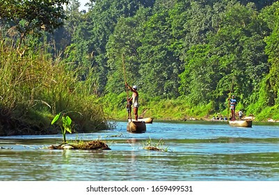 CHITWAN, NEPAL - OCTOBER 15, 2008: Local man traveling by rowboat at wild river in Chitwan National Park. Park was established in 1973 and granted the status of a World Heritage Site in 1984