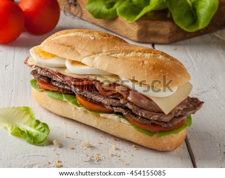 Chivito is a typical sandwich from Uruguay, with lettuce, tomato, bacon, beef, fried or boiled eggs and cheese.