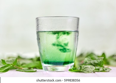 Chlorophyll In Glass Of Water With Fresh Green Mint On White Table