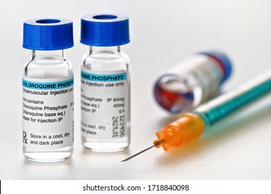 Chloroquine phosphate (generic name) drug in small injection bottles with blue caps, orange green syringe near (own label design with dummy data - not real product) Potential coronavirus cure concept - Powered by Shutterstock