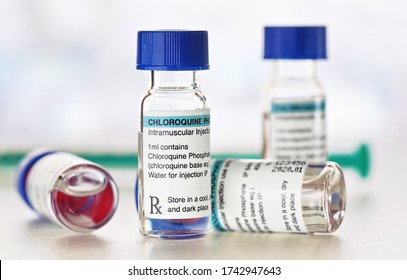 Chloroquine phosphate (generic name) drug in small injection bottles with blue caps, blurred syringe background (own label design with dummy data - not real product) Potential coronavirus cure concept - Powered by Shutterstock