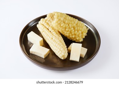 Choclo con queso a typical ecuadorian appetizer that consists of corncob accompanied by fresh cheese. It’s on a white background. 