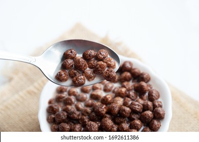 Chocolate balls with milk and a spoon in a white plate
