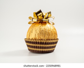 Chocolate balls wrapped in golden paper. Chocolate bar with golden bow. close-up.