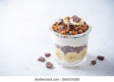 Chocolate and banana Greek yogurt granola parfait in a glass. toning. selective focus