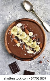 Chocolate banana smoothie bowl with nuts and chia seeds on a grey concrete,stone or slate background.Top view.