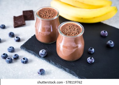 Chocolate banana smoothie with chia seeds and blueberry on a slate and stone background