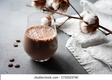 Chocolate and banana smoothie in glass. Grey background.