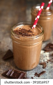 Chocolate banana smoothie on a rustic wooden background.