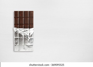 Chocolate Bar In Foil On Wooden Table Top View