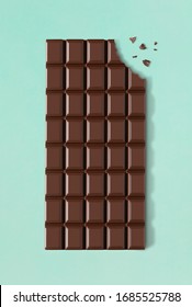 Chocolate bar with a missing bite on green background