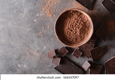  Chocolate bar pieces and  cocoa powder on gray abstract background.  